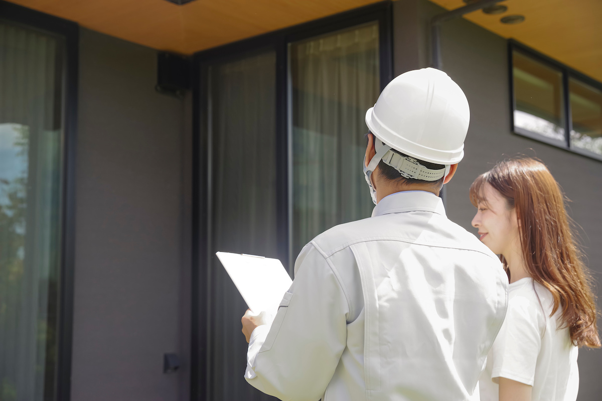 戸建て住宅の前でお客様と住まいを確認するスタッフ